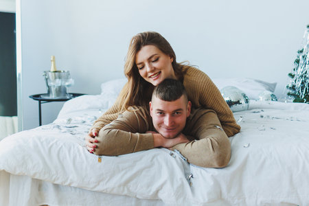 A joyful couple is sharing and enjoying a cozy, intimate moment together in a beautifully decorated bedroom that reflects their love and the spirit of celebration they embodyの写真素材