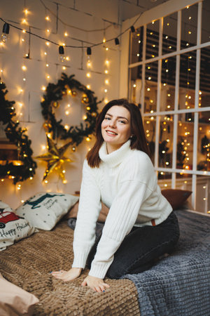 Cute girl in New Year's locations in a cozy living room. Woman at home for the new year.の写真素材