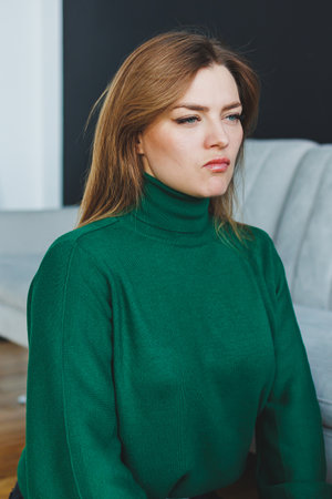 A poised, elegant woman, dressed in a stylish green turtleneck, is elegantly posed in a serene indoor environment, radiating both confidence and beauty in every aspectの写真素材