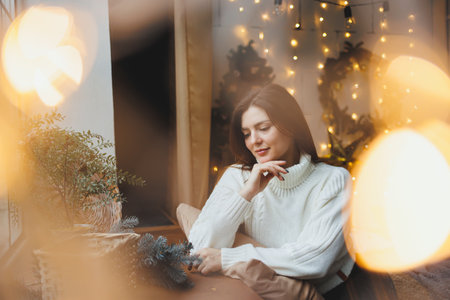 Cute girl in New Year's locations in a cozy living room. Woman at home for the new year.の写真素材