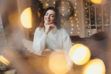 Cute girl in New Year's locations in a cozy living room. Woman at home for the new year.の写真素材
