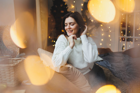 Cute girl in New Year's locations in a cozy living room. Woman at home for the new year.の写真素材