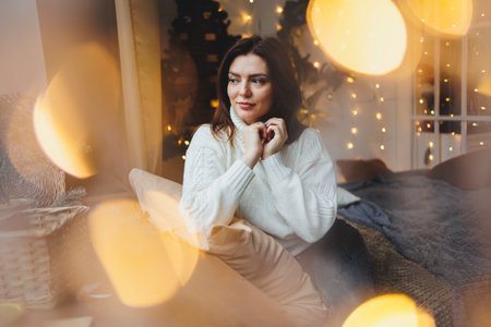 Cute girl in New Year's locations in a cozy living room. Woman at home for the new year.の写真素材