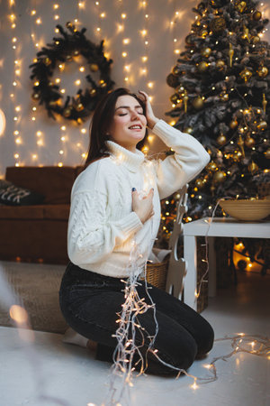 Cute girl in New Year's locations in a cozy living room. Woman at home for the new year.の写真素材
