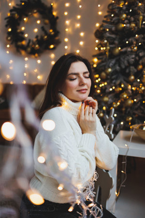 Cute girl in New Year's locations in a cozy living room. Woman at home for the new year.の写真素材