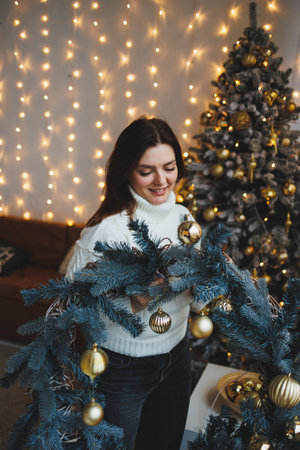 Cute girl in New Year's locations in a cozy living room. Woman at home for the new year.の写真素材