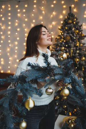 Cute girl in New Year's locations in a cozy living room. Woman at home for the new year.の写真素材