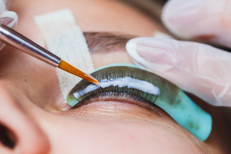 A skilled technician applies beautiful eyelash extensions with precision tools, showcasing the intricate process in a serene beauty salon, highlighting the artistry involvedの写真素材