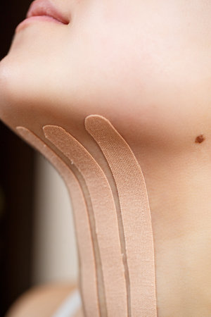 Close-up of a tape on the neck of a young woman. Kinesiotherapy with therapeutic tapesの写真素材