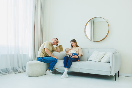 A loving family scene shows devoted parents nurturing their baby in a cozy living room filled with warm light and inviting textures, creating comfort and serenityの写真素材