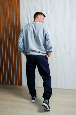 The image features a stylish man in a gray sweatshirt and navy jogger pants, ideal for casual outings and athletic settings, blending modern fashion with comfortの写真素材