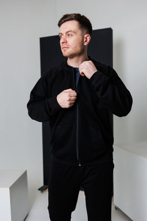 In a vibrant studio, a young man showcases a stylish black sports jacket, highlighting his unique sense of style and captivating everyone with his fashionable presenceの写真素材