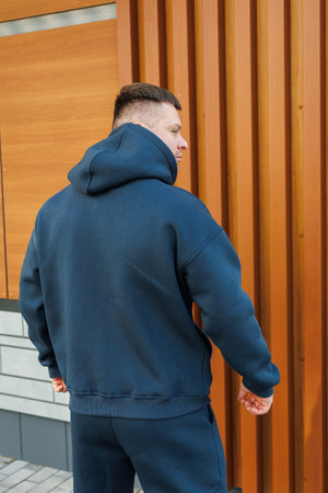 A fashionable young man wearing a dark hoodie exemplifies the essence of casual urban fashion, making it an ideal choice for lifestyle and fashion stock imagery designの写真素材