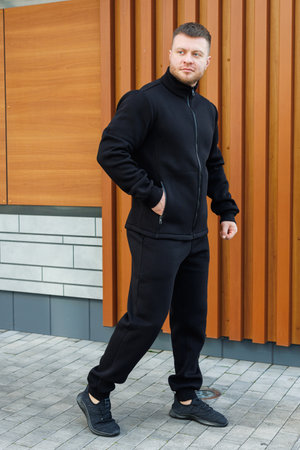 A young person confidently poses in a stylish black outfit that perfectly blends contemporary fashion with comfort, all set against a modern wooden backdrop full of characterの写真素材