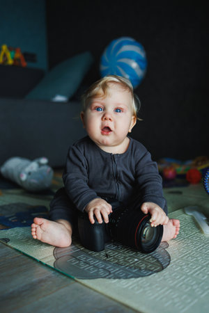 An adorable baby sits joyfully on a colorful playmat surrounded by engaging toys, capturing the essence of childhood curiosity and happiness in a warm, loving homeの写真素材
