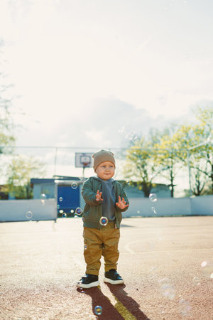 Little cute boy 2 years old running with soap bubbles. Boy catching soap bubbles in the park,...