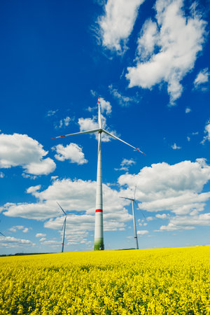 Wind turbine on sky background and grass with farmland for eco friendly environment or alternative...