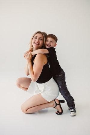 Mom and 4 year old son smiling and hugging on a white background. Warm relationship between mom and son. Concept of family relationships between mom and son.の写真素材