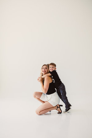 Cute mother and boy hugging while sitting on white background. Happy mother and baby son waiting for dad to return from work. Fun games of mother and son.の写真素材