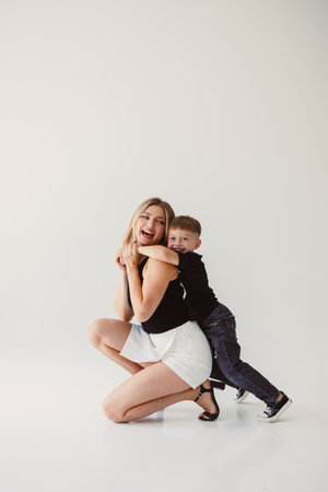 Cute mother and baby boy hugging while sitting on white background. Happy mother and baby son waiting for dad to return from work. Fun games of mother and son.の写真素材