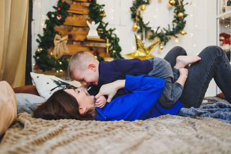 Mom spends time with her son on New Year's Eve at home. Holiday games of mom with son at home. Cheerful childhood.の写真素材