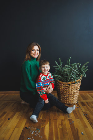 Mother and little son at home on Christmas, child smiles at mother, congratulates and gives unexpected gift. Woman mother receives gift from son on birthday. Family holiday, love conceptの写真素材