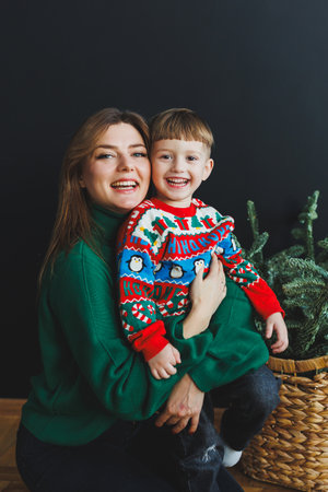 Mother and little son at home on Christmas, child smiles at mother, congratulates and gives unexpected gift. Family holiday, love conceptの写真素材