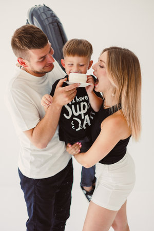 Happy young family dad, mom and boy around birthday cake. Celebrating children's birthday in family circle.の写真素材