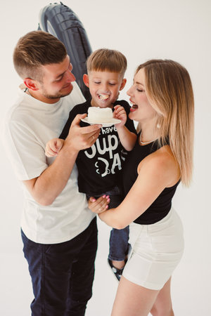 Mom, dad and son celebrate their son's birthday. 4 year old boy eats sweet birthday cake.の写真素材
