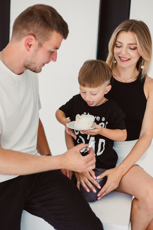 Mom, dad and son celebrate their son's birthday. 4 year old boy eats sweet birthday cake.の写真素材
