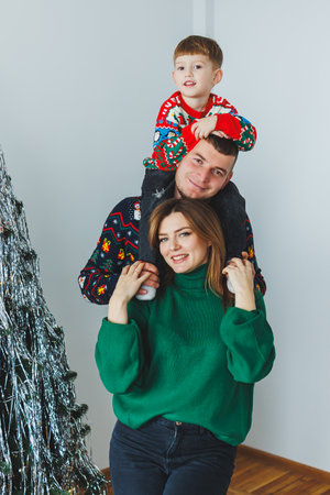 A beautiful family joyously captures the warmth of the holiday season with a playful child gleefully perched on dads shoulders, all surrounded by festive Christmas decorationsの写真素材