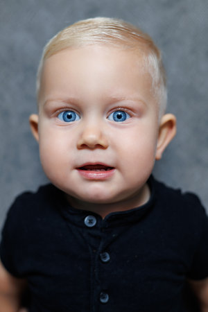 A heartwarming image of an utterly adorable baby, showcasing captivating blue eyes and soft, golden blonde hair, creating a wonderfully charming presence in a neutral settingの写真素材