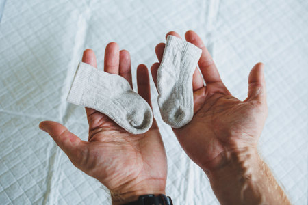 A pair of adorable baby socks in loving hands beautifully captures the essence of love and the joy of welcoming new life, enriching hearts with warmth and tendernessの写真素材