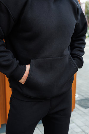This trendy black hoodie with a unique texture pairs perfectly with fitted joggers for a stylish streetwear outfit that combines comfort and fashion effortlesslyの写真素材