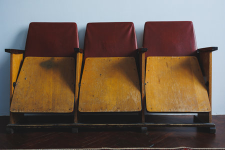 This striking image shows a charming trio of vintage theater seats with a classic design in red and...