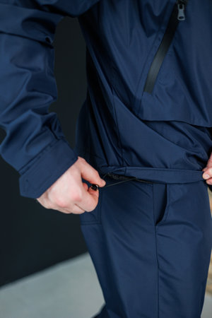A stylish individual adjusts the hem of a beautifully designed navy jacket, emphasizing its unique features and functionality for outdoor activities and fashionの写真素材