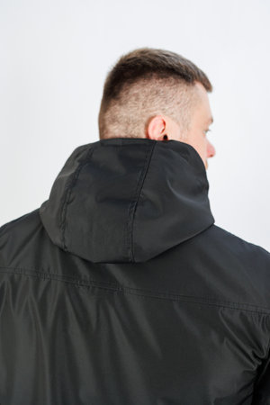 A fashionable young man wearing a sleek black hooded jacket is seen from behind, perfectly showcasing various contemporary urban fashion styles and exciting apparel promotionsの写真素材