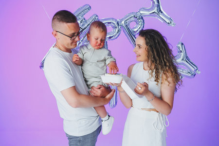 A joyful family celebrates special moments with their precious baby, marking milestones of growth and love against a vibrant purple backdrop that enhances their warmthの写真素材