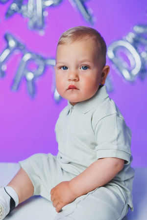 Birthday of a 1 year old boy. A small one year old boy in a t-shirt runs and laughs around the room. A toddler boy is happy and smiling.の写真素材