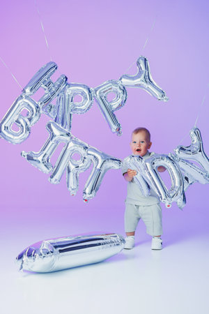 A little one-year-old boy in a t-shirt runs and laughs around the room. A toddler boy is happy and smiling.の写真素材