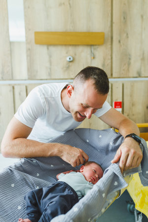 A father tenderly interacts with his newborn in the hospital nursery, showcasing the deep love and bond that defines the joys of parenthood in this precious momentの写真素材