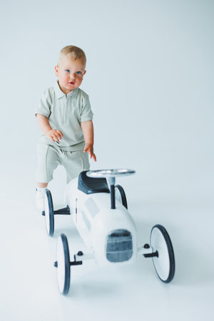 A joyful and active young child engages with a vintage toy car in a bright and airy studio, perfectly showcasing their playful innocence and the magic of imaginative playの写真素材