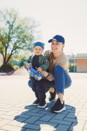 On a bright day, a loving mother joyfully plays with her energetic child outdoors, enhancing their family bond through warmth, laughter, and quality time togetherの写真素材