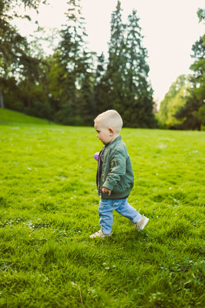 Cute boy running on the grass. Carefree childhood with joyful laughter of a child. Toddler having fun and enjoying a walk in nature.の写真素材
