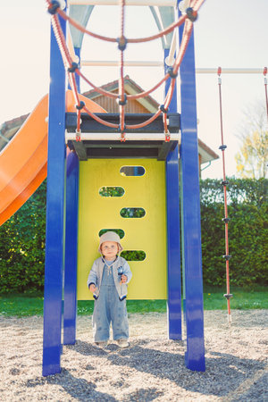 Toddler playing on the playground. 2 year old boy on green grass in the park, enjoying a sunny summer day. Activities for children in nature.の写真素材