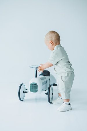 In a bright studio, a cheerful toddler joyfully plays with a charming vintage rideon toy car, embodying the beauty of youthful exploration and playful innocenceの写真素材