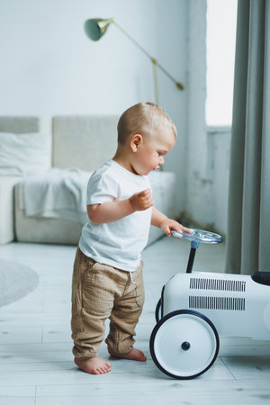 A little one-year-old boy in a t-shirt runs and laughs around the room. A toddler boy is happy and smiling.の写真素材