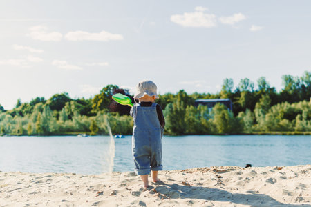 Happy 2 year old little boy playing on sand during summer vacation, wearing hat. Family travel and vacation, outdoor activities on summer beach holiday with children.の写真素材