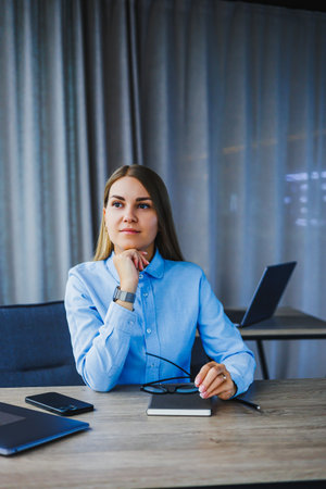 A young businesswoman is thoughtfully pondering her next career moves in her sleek, contemporary...