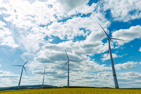 Wind turbine on grassy field against blue sky in countryside. Wind farm in farmland in Europe. Wind power plant generating electricityの写真素材